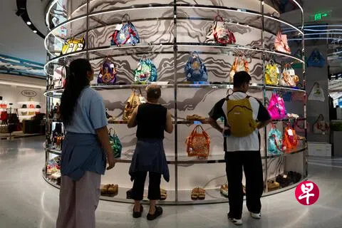 图为7月8日在北京，人们在一家购物中心的箱包店里观看陈列的各色包袋。（路透社）