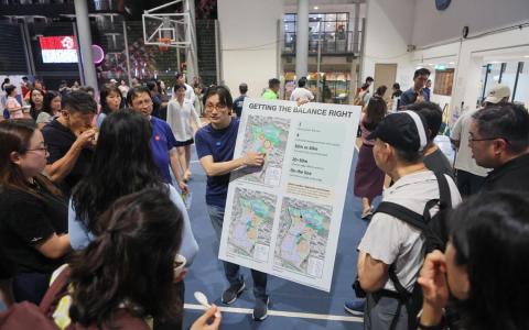 一名居民在直落布兰雅民众俱乐部举行的吉门营房公众交流会前，展示亲手制作的看板，向其他居民说明他对建屋局环境研究报告的质疑，以及准备在会上提出的观点。（张俊杰摄）